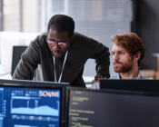 Two mem looking at a computer monitor