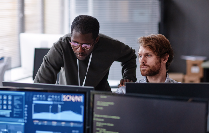 Two mem looking at a computer monitor